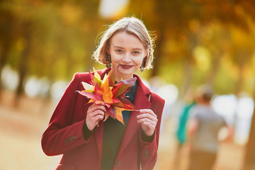 Young woman with bunch of colorful autumn leaves