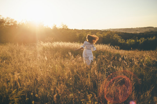 young beautiful girl is running sunset in white dress