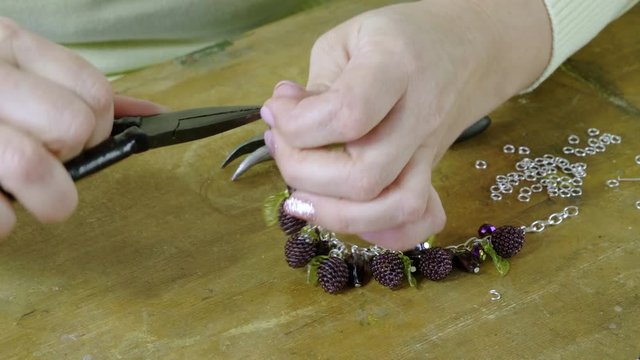 The young woman creating handmade jewelry bracelet in the studio. 4K