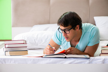 Student preparing for exams at home in bedroom lying on the bed