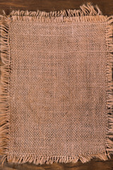 Linen fabric with fringed edges on wooden background, copy space.