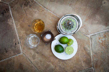 Glasses of tequila and limes on plate