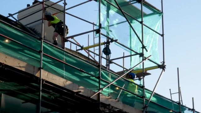 Construction workers tossing building materials to each other.
