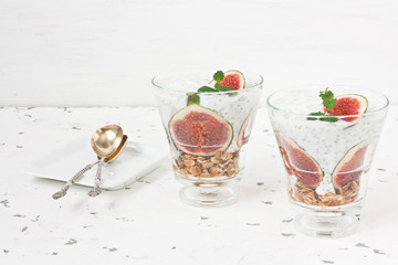 Chia seeds pudding parfait / Chia seeds pudding parfait with yogurt, figs, oatmeal granola, and mint in glass on white background
