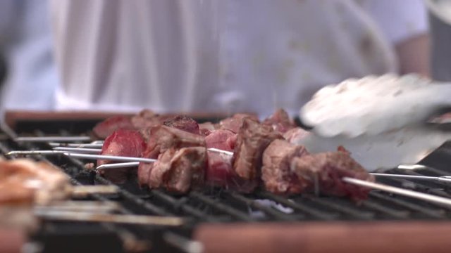 Beef kebabs on skewers being cooked, seasoned with salt and turned on a hot barbecue grill.