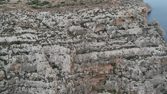 Paning down to reveal shot of cliff in Malta near blue groto