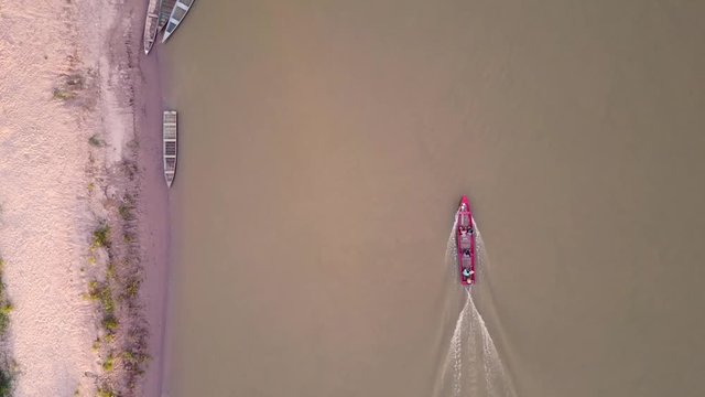 Top down shot of a red boat on the Envira river of a village Nova Morada in Brazil