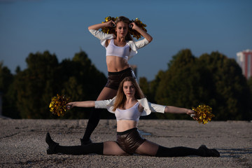 Two girls cheerleaders with pompons posing outdoors