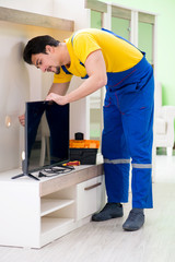 Male professional serviceman repairing tv at home