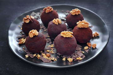 Close-up on a dark plate of rum balls decorated with wallnuts