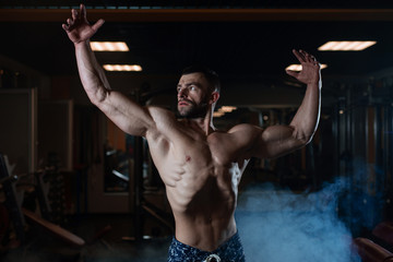 Fototapeta na wymiar Athletic man with a muscular body poses in the gym, showing off his muscles. The concept of a healthy lifestyle