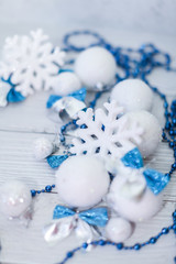Christmas or new year composition in silver white and blue colors with balls snowflake bows and beads on white wood