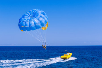 Parasailing water amusement - flying on a parachute behind a boat on a summer holiday by the sea in...