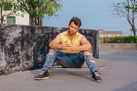 Young man sitting on the longboard on the street.
