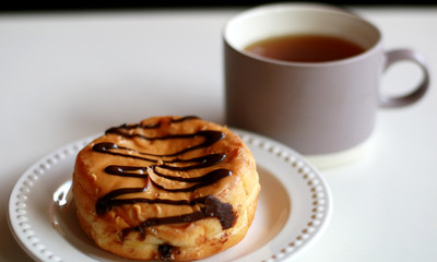 Delicious chocolate doughnut and a glass of tea.