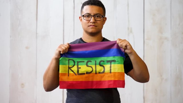 Queer black person holding a resist pride fag