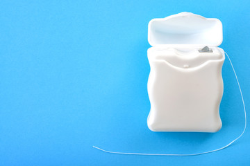 Dental hygiene and oral health concept with a dental floss box isolated on blue background with...