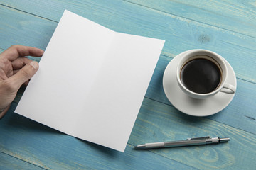 Mens hand holding white booklet