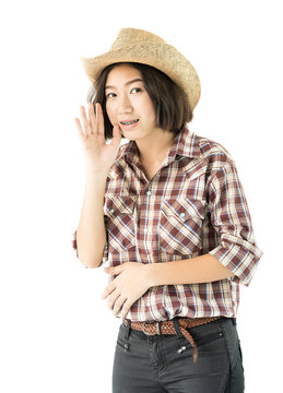 Young woman in a cowboy hat and plaid shirt with hand on her hat