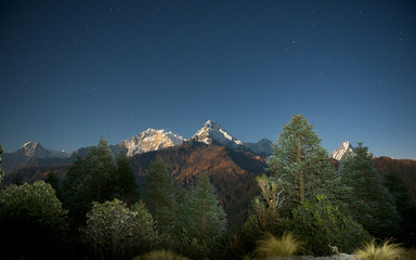 Annapurna mountain range lit by the moon and the stars under the light of a full moon