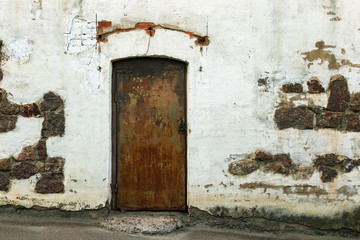 Shabby building facade with closed door. Old white wall. Historical Old building.