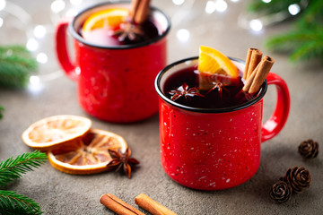 Two cups of christmas mulled wine or gluhwein with spices and orange slices on rustic table top view. Traditional drink on winter holiday