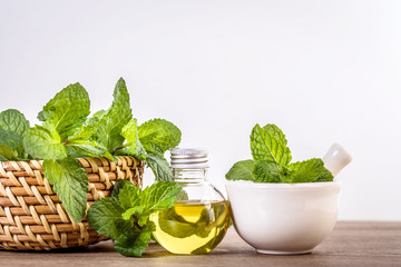 Aroma essential oil from a peppermint in the bottle on the table with fresh green mint leaf © Cozine