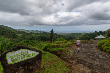 Signpost to cascade waterfalls at the beautiful holiday island Mauritius with a woman walking shot from behind not recognizable.