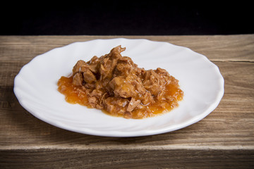 wet food on a white plate on a wooden dark background