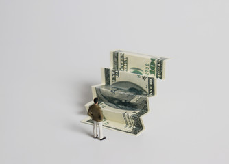 The back of a miniature man standing in front of a bill folded in steps.