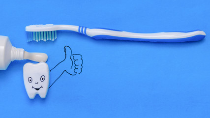 Tooth figurine with funny face and hand shows the class of toothpaste and brush. The view from the top. Flat lay.