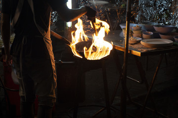 A chef is preparing a delicious meal in a fiery wok at his street food vending stall