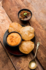 Suji/Sooji Halwa Puri or Shira Poori with black chana masala breakfast, served in a plate and bowl. selective focus