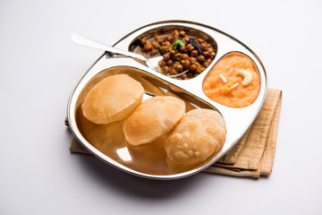 Suji/Sooji Halwa Puri or Shira Poori with black chana masala breakfast, served in a plate and bowl. selective focus