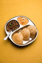 Suji/Sooji Halwa Puri or Shira Poori with black chana masala breakfast, served in a plate and bowl. selective focus