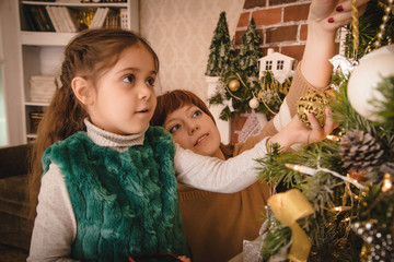 Mom and daughter in the room decorated for Christmas. Loving family indoors