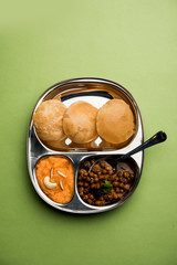 Suji/Sooji Halwa Puri or Shira Poori with black chana masala breakfast, served in a plate and bowl. selective focus