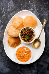 Suji/Sooji Halwa Puri or Shira Poori with black chana masala breakfast, served in a plate and bowl....