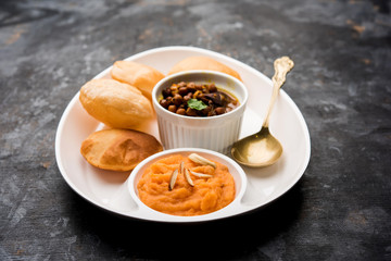 Suji/Sooji Halwa Puri or Shira Poori with black chana masala breakfast, served in a plate and bowl. selective focus