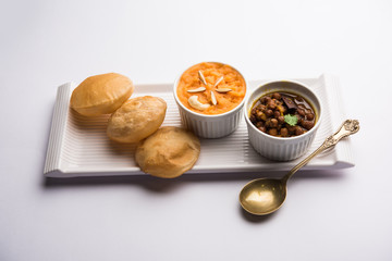 Suji/Sooji Halwa Puri or Shira Poori with black chana masala breakfast, served in a plate and bowl. selective focus