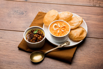 Suji/Sooji Halwa Puri or Shira Poori with black chana masala breakfast, served in a plate and bowl....