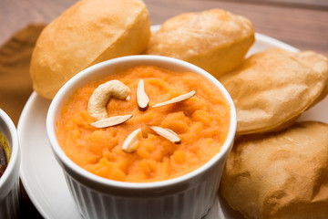Suji/Sooji Halwa Puri or Shira Poori with black chana masala breakfast, served in a plate and bowl. selective focus