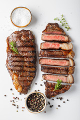 Two grilled marbled beef steaks striploin with spices isolated on white background, top view