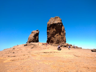 Fototapeta premium iconic famous mountain called Roque Nublo in Canary Islands Spain with people trekking in a clear blue day of summer