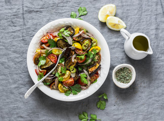 Mediterranean style baked eggplant, fresh cherry tomatoes and cilantro salad - healthy delicious snack, appetizers, tapas on grey background, top view