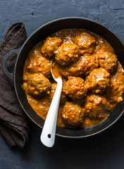 Lentils meatballs in curry sauce in cooking pan - vegetarian food in Indian style. Healthy eating concept. Top view, on a dark background