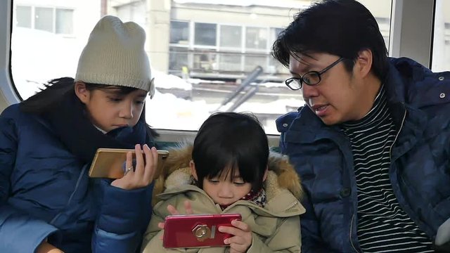 Asian family using mobile phone while travle by local train in japan slow motion 