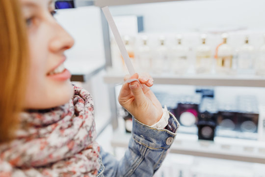 Young woman choosing a perfume in cosmetic shop