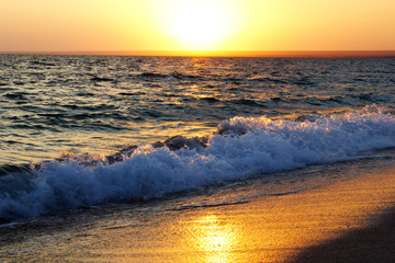 Naklejka premium Sunset on the sea on the beach. Bright yellow sunset. The wave on the beach at sunset. 