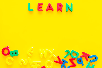 Fototapeta na wymiar Children learn read concept. Word learn written by plastic letters on yellow background top view copy space